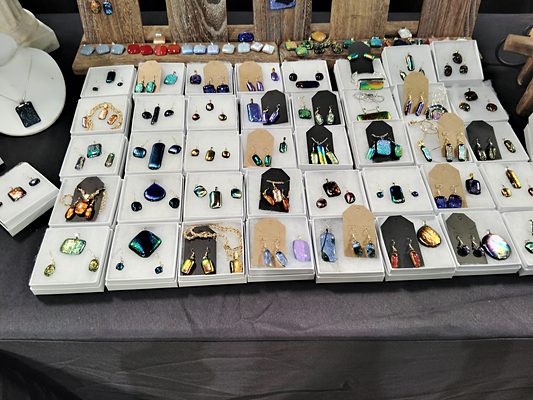 Dozens of boxed pendants and earrings laid out on the booth table