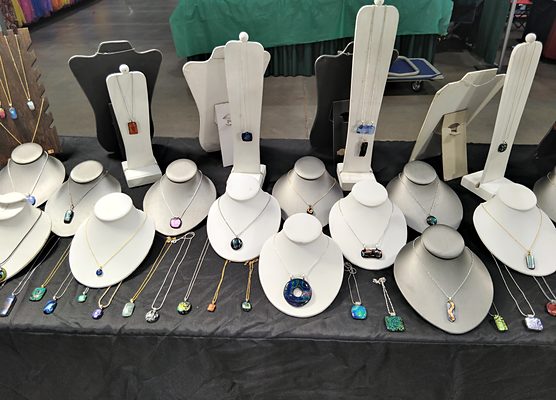 Her booth table: rows of glass pendants on white display busts