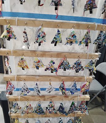 Rows of small fused-glass Christmas tree ornaments in many colour mixes, hanging on display rails