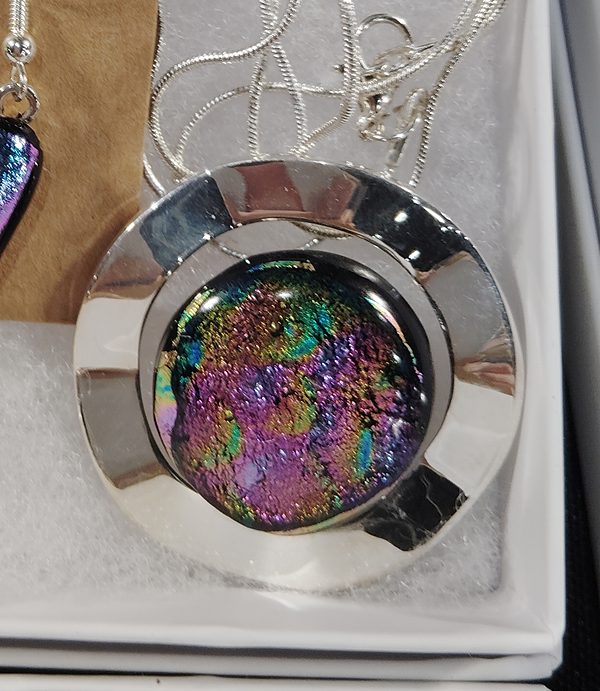 Round pendant in a wide polished silver frame with rainbow sparkle glass inside