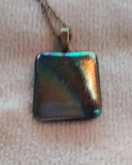 Square dark glass pendant with a diagonal band of orange and teal, bronze chain