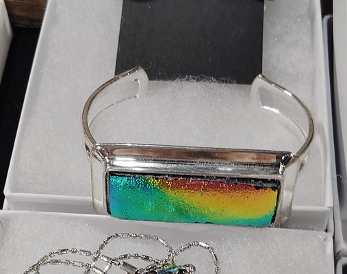 Silver cuff bracelet set with a long bar of green-to-magenta glass